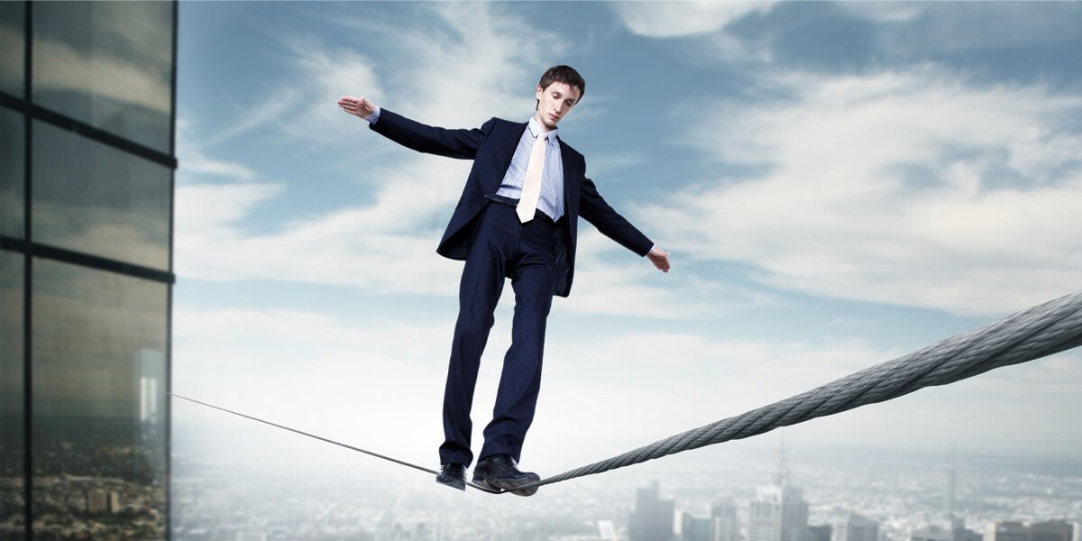 A man in a suit carefully walks on a tightrope