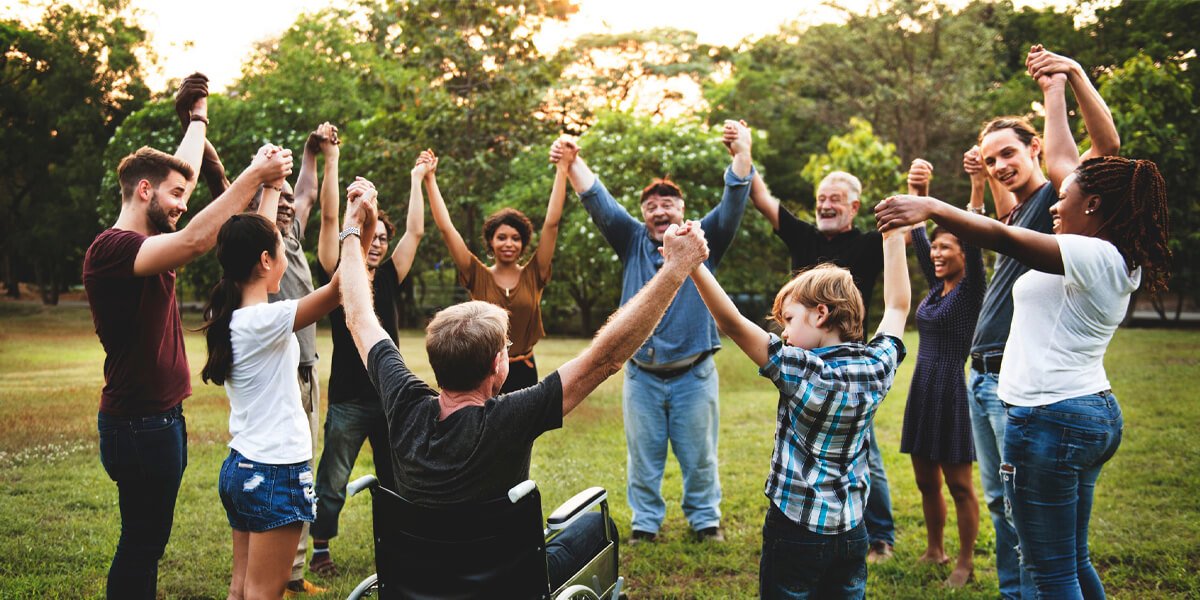 A number of individuals with raised hands in a grassy field