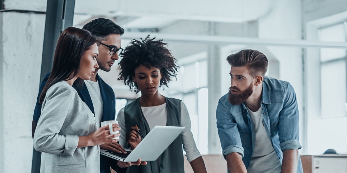 Three professionals discussing work around a laptop