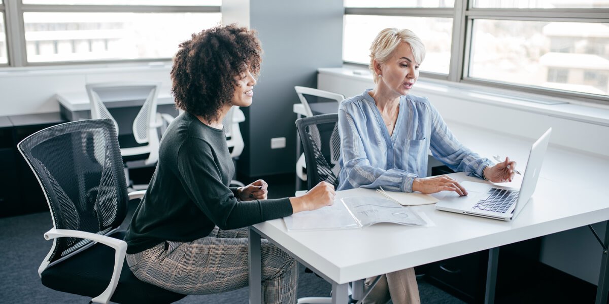 Two women working on laptops at a table