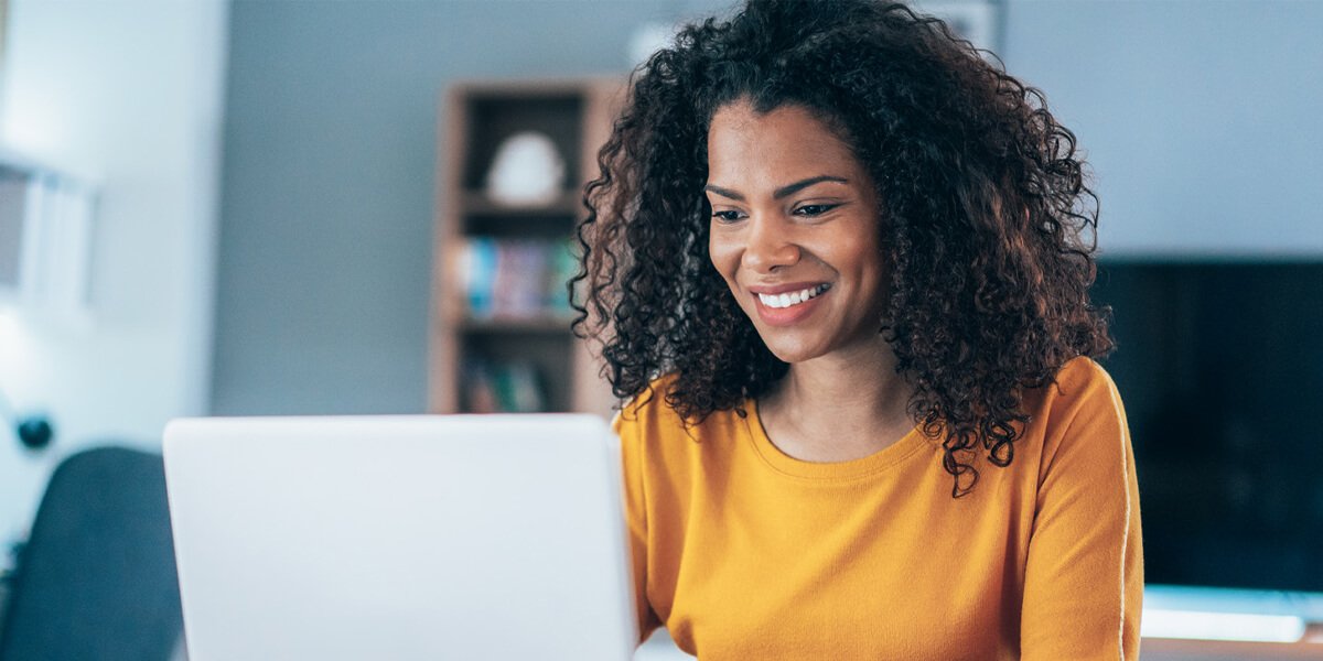 Smiling woman with curly hair wearing a yellow shirt