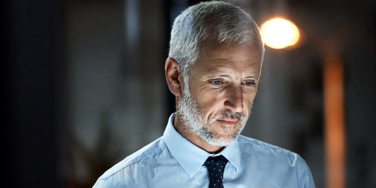 Bearded man in tie gazes at computer screen, deep in concentration