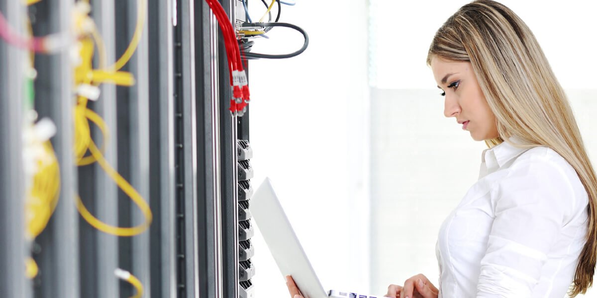 A woman in a white shirt typing on a laptop