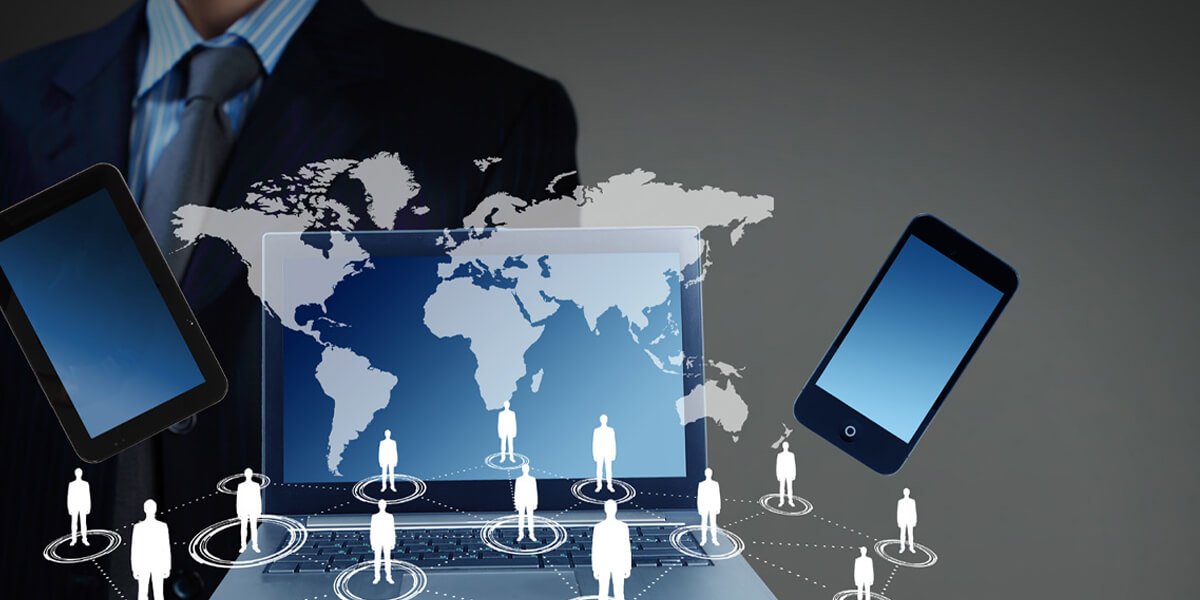 A man in a business suit using a laptop and surrounded by various mobile devices