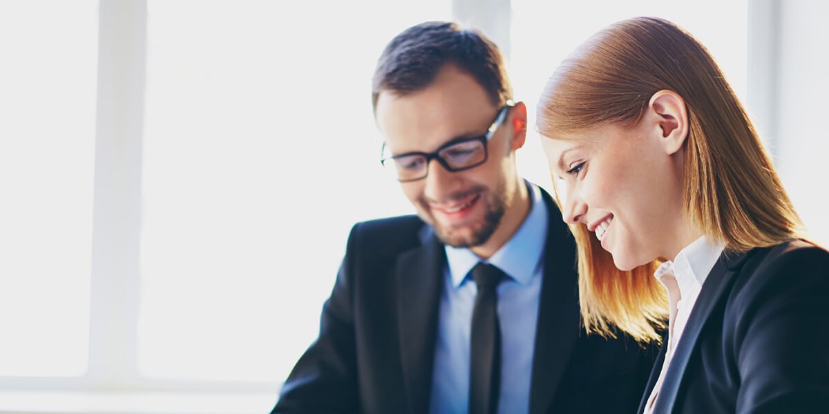 Professional man and woman in suits examining laptop together